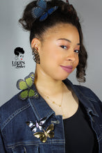 Load image into Gallery viewer, Woman wearing both gold and silver Ascend Brooches on a denim jacket, showcasing modern butterfly pins from the Take Flight Collection by Loops and Lashes.