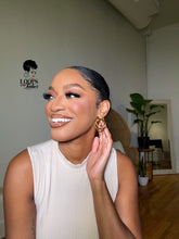 Load image into Gallery viewer, A woman wearing QuintEssential Loops earrings. These gold PVD plated stainless steel earrings feature a snap bar closure (for pierced ears) and create the illusion of five hoops in one. Dimensions: 1.61 in length x 1.38 in width.