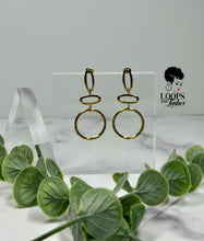 Load image into Gallery viewer, Elevate your style with 'Gilded Grace' Gold Earrings, boasting a minimalist geometric design with textured metal. These high-quality stainless steel dangle earrings are lightweight and graceful, featuring three vertically stacked circular/oval shapes for an added touch of elegance. Find your perfect accessory today and embrace the subtle sophistication of Gilded Grace.