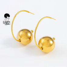 Load image into Gallery viewer, Gold hoop earrings with spherical ball on a white background, featuring the Loops and Lashes brand.