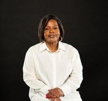 Load image into Gallery viewer, A woman wearing the Heritage Hoops, two-inch gold-plated stainless steel open hoop earrings with a unique textured design. These waterproof, tarnish-resistant hoops feature an exclusive engraved submark logo, symbolizing elegance and empowerment. Lightweight yet bold, they add a timeless touch to any look