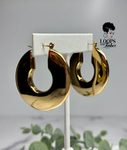 Load image into Gallery viewer, Crafted from high-quality stainless steel and meticulously PVD gold plated, the Regal Rounds are the epitome of luxury. With a bold design that effortlessly catches light, these hoops ensure you're the center of attention on any occasion. The durable stainless steel guarantees long-term use, while the PVD gold plating adds a lustrous, enduring finish. Elevate your look with the timeless allure of Regal Rounds today.