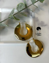 Load image into Gallery viewer, Crafted from high-quality stainless steel and meticulously PVD gold plated, the Regal Rounds are the epitome of luxury. With a bold design that effortlessly catches light, these hoops ensure you're the center of attention on any occasion. The durable stainless steel guarantees long-term use, while the PVD gold plating adds a lustrous, enduring finish. Elevate your look with the timeless allure of Regal Rounds today.