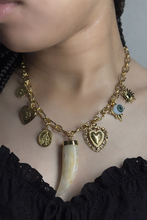 Load image into Gallery viewer, Necklace with gold charms and a large tusk pendant worn by a woman.