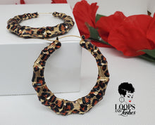Load image into Gallery viewer, The picture is of a pair of bamboo earrings made from lightweight iron alloy material. They are in a circular hoop shape and have a leopard print design on them. The earrings have a gold-toned metal stem that goes through the earlobe.
