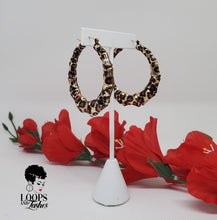 Load image into Gallery viewer, The picture is of a pair of bamboo earrings made from lightweight iron alloy material. They are in a circular hoop shape and have a leopard print design on them. The earrings have a gold-toned metal stem that goes through the earlobe.