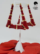 Load image into Gallery viewer, The picture is of a pair of lightweight earrings made in a classic bamboo style. The earrings are decorated with a red enamel finish,. The earrings have a trapezoidal shape and a gold-toned metal stem that goes through the earlobe.