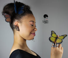 Load image into Gallery viewer, Woman wearing the Monarch Ring gazes at a butterfly resting on her hand, symbolizing transformation and elegance. Silver butterfly ring shines in natural light.
