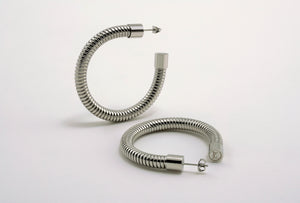 A pair of Heritage Hoops in sleek silver, crafted from high-quality stainless steel with a durable PVD plating. These two-inch open hoop earrings feature a unique textured design and an exclusive engraved submark logo, symbolizing timeless elegance and empowerment. Waterproof and tarnish-resistant, they blend modern sophistication with lasting quality.