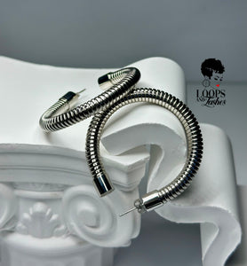 A pair of Heritage Hoops in sleek silver, crafted from high-quality stainless steel with a durable PVD plating. These two-inch open hoop earrings feature a unique textured design and an exclusive engraved submark logo, symbolizing timeless elegance and empowerment. Waterproof and tarnish-resistant, they blend modern sophistication with lasting quality.