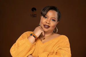 The picture is of a woman wearing a pair of bamboo earrings made from lightweight iron alloy material. They are in a circular hoop shape and have a leopard print design on them. The earrings have a gold-toned metal stem that goes through the earlobe.